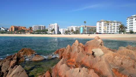 images on rocks of a mediterranean beach with buildings in the background fenals lloret de mar