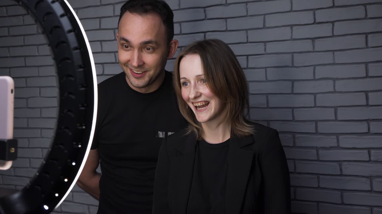 video de una pareja hablando con sus seguidores en el fondo de una pared de ladrillo