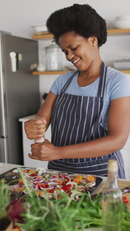video vertical de una feliz mujer afroamericana cocinando en casa
