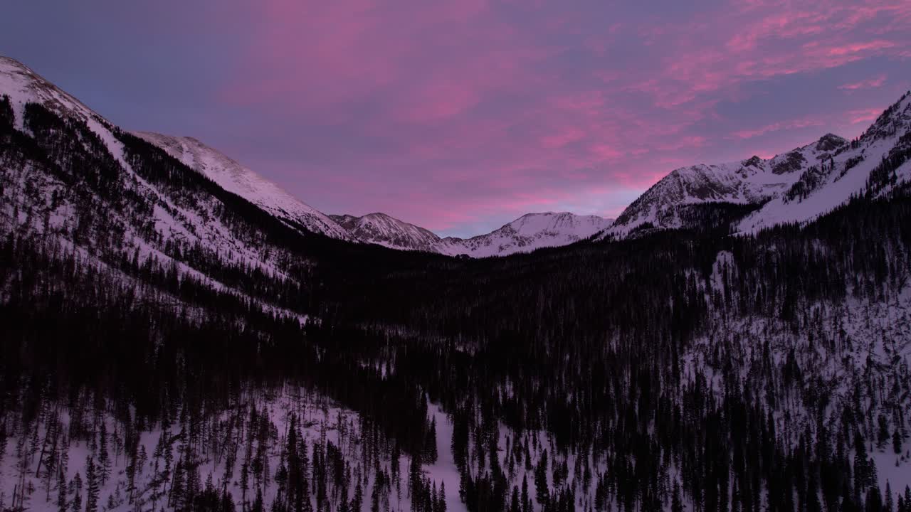 Vista di una valle tra due montagne innevate durante un tramonto colorato