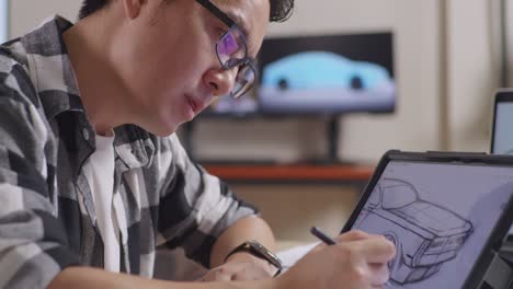 close up of asian male having a headache while drawing new car design concept on a tablet in the studio with tv and computers display 3d electric car model