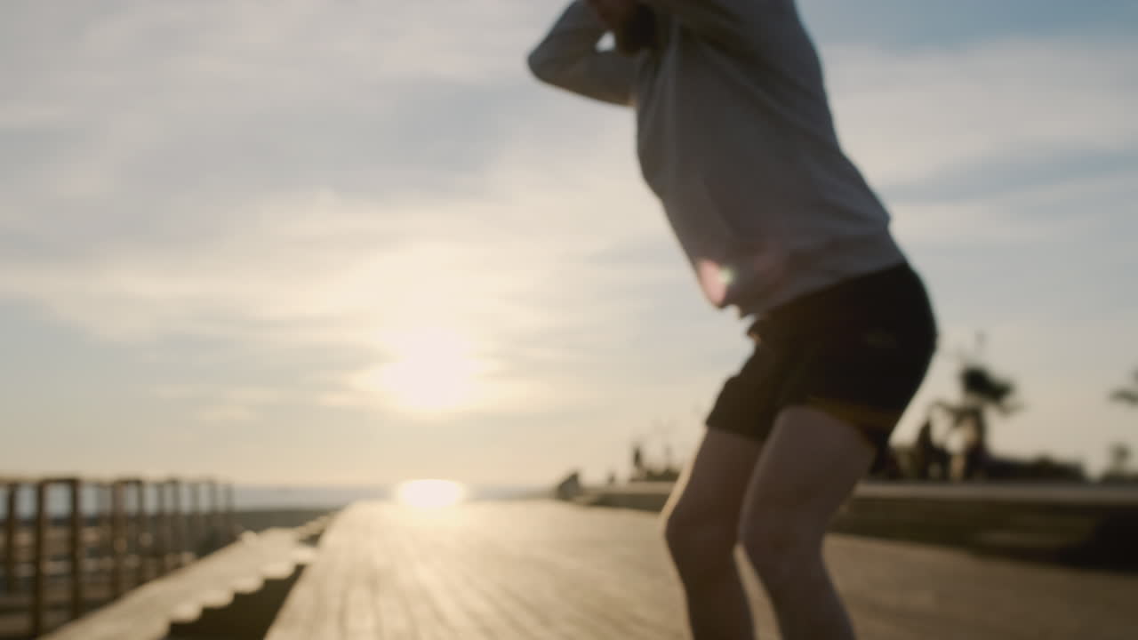 해가 뜨면 해변의 산책로에서 을 하는 남자