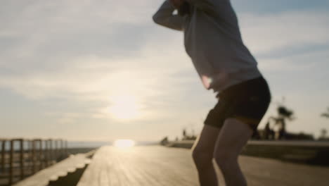 hombre haciendo sentadillas en un paseo marítimo de la playa al amanecer