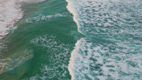el océano azul profundo la orilla de la mar espumosa la playa ondulada en verano el surfista acostado la tabla de surf