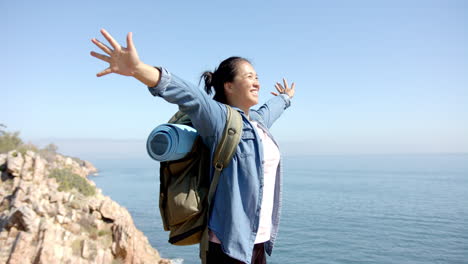 hiking on mountain, woman with backpack and yoga mat enjoying ocean view