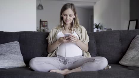 calm pregnant woman listening to music from smartphone