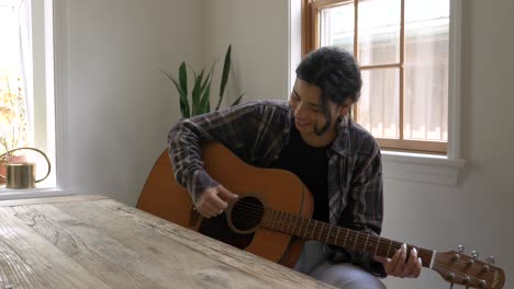 Creative-Puerto-Rican-female-teenager-playing-acoustic-guitar-behind-rustic-wooden-table