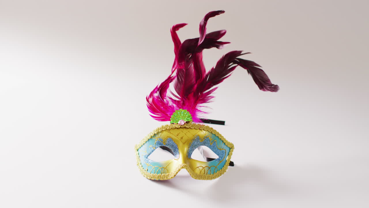 Video di maschera di carnevale gialla e blu con piume rosa su sfondo bianco con spazio per il testo