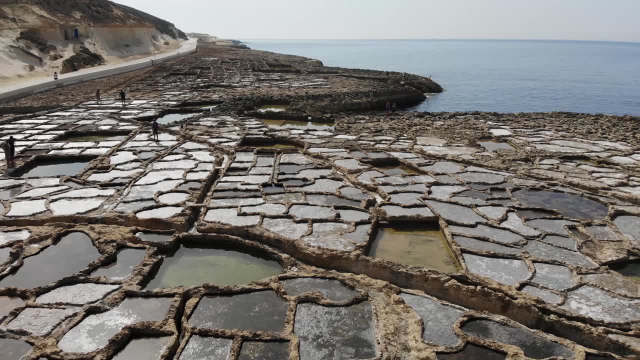 몰타에 있는 고조 섬의 고대 암염 팬을 가로질러 역방향으로 날아가는 공중 드론
