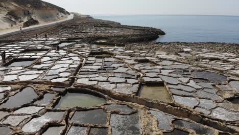 An-aerial-drone-shot-flying-in-reverse-across-the-ancient-rocky-Salt-Pans-of-Gozo-Island-in-Malta