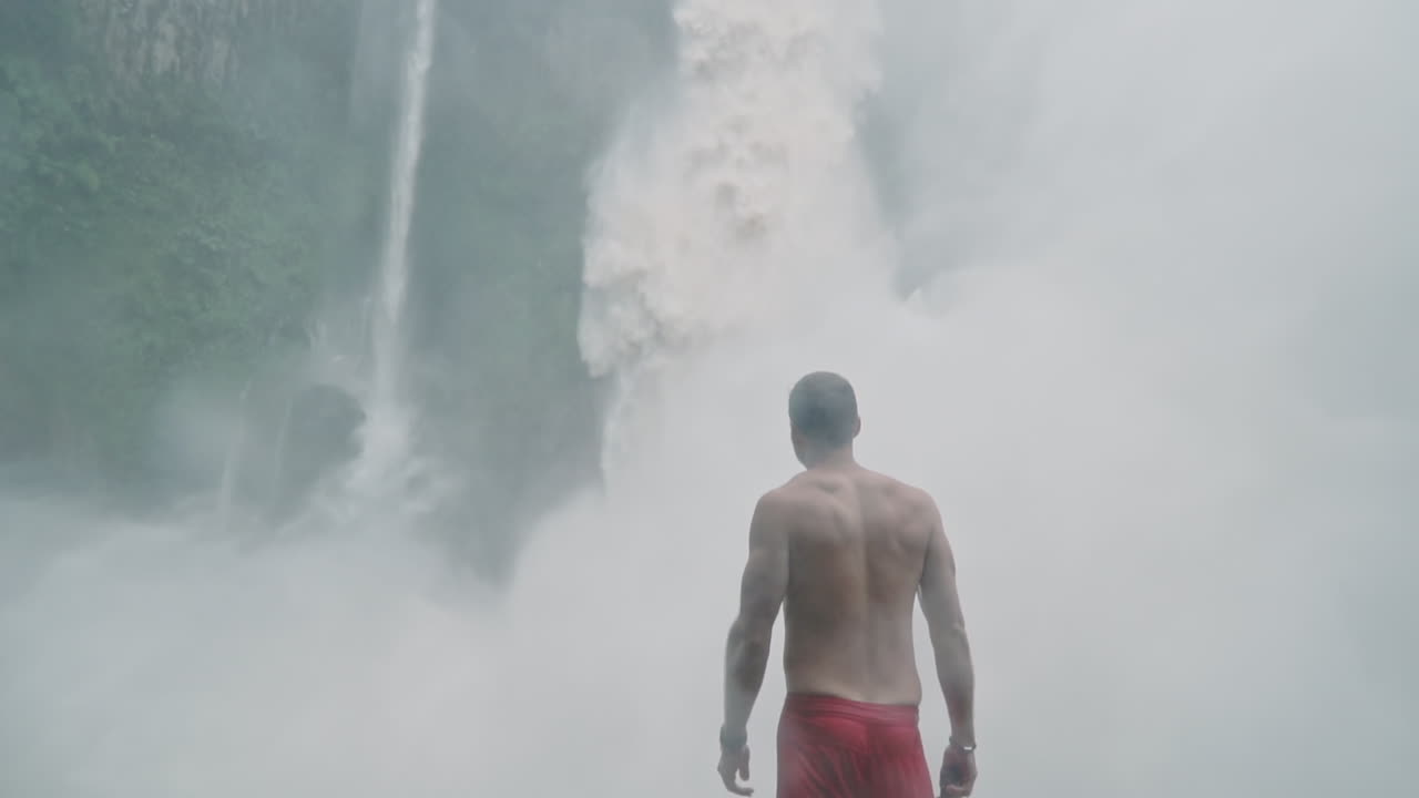 Man looks up at roaring Bajos del Toro waterfall in Costa Rica, slow motion