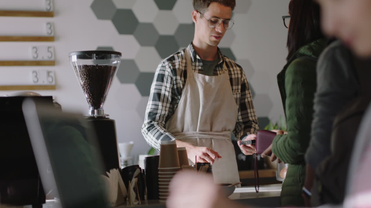 cassiere felice uomo che lavora in un caffè affollato barista che serve i clienti che comprano caffè che sostiene piccole imprese donna che usa un computer portatile che gode di un ristorante vibrante