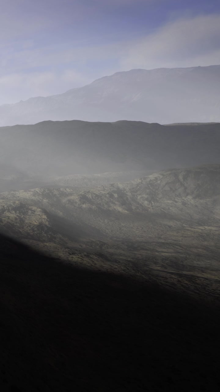 Distant mountains and valley lit by soft light during early morning hours