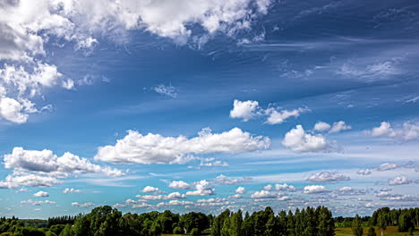 fluffy clouds blowing in one direction with a wind shear pushing wispy cirrus clouds in another over a forest - time lapse