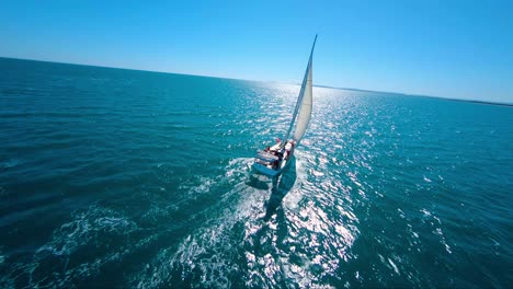 acrobatic cinematic shot of a sailboat racing through the tropical ocean