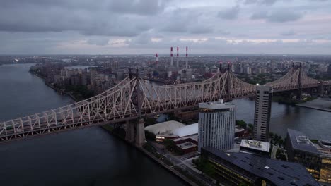 Aerial-view-away-from-the-Queensboro-Bridge,-cloudy-evening-in-NYC,-USA---rotating,-pull-back,-drone-shot