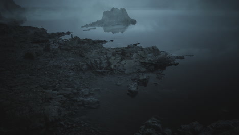 misty lake landscape at dawn with a rocky island and calm waters