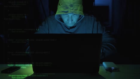 focus male hacker typing security code on laptop computer seen on the left side screen. - close up