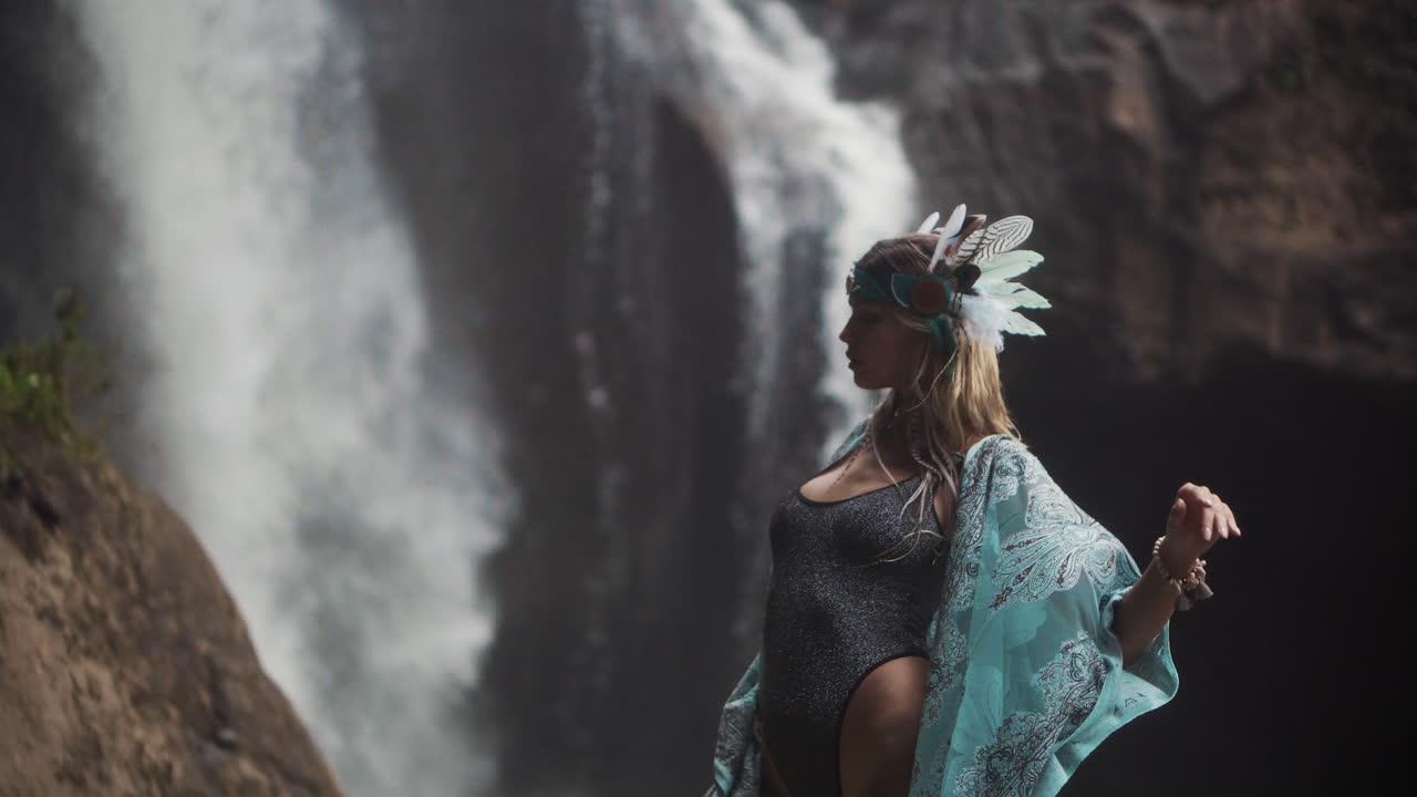 mujer con vestido turquesa junto a la cascada