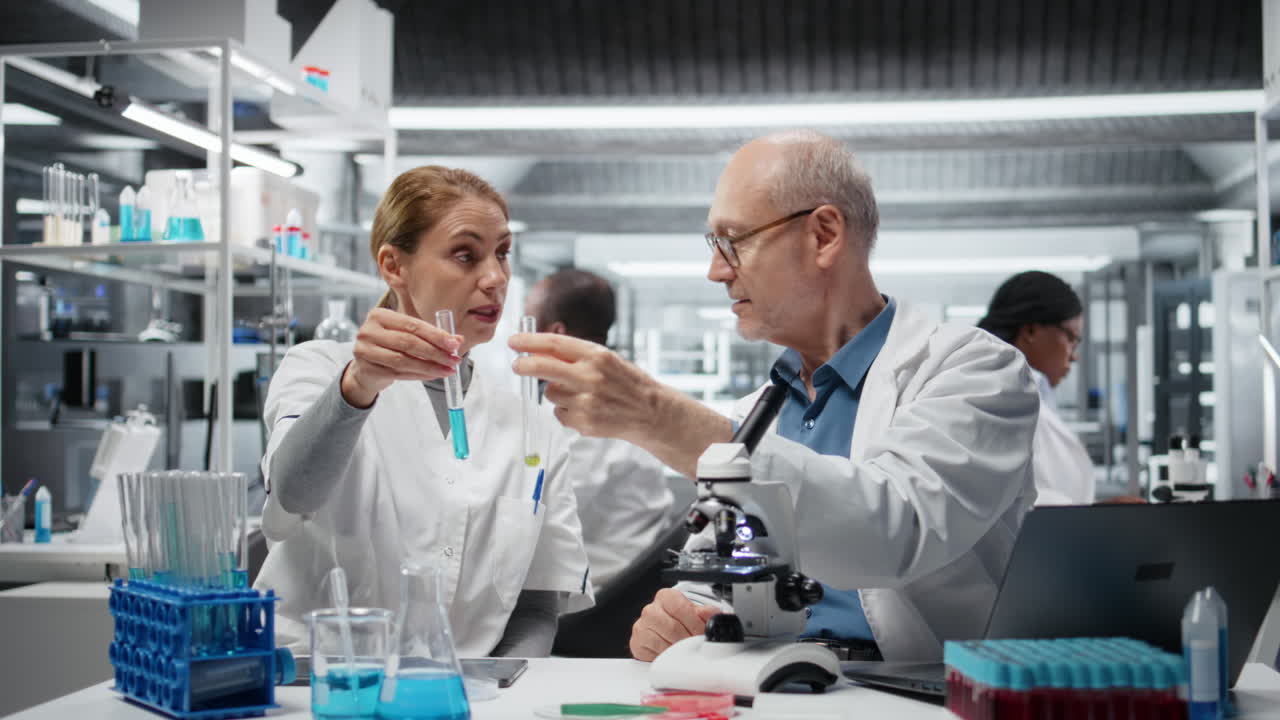 Lab team leader teaching intern to analyze liquid polymer properties