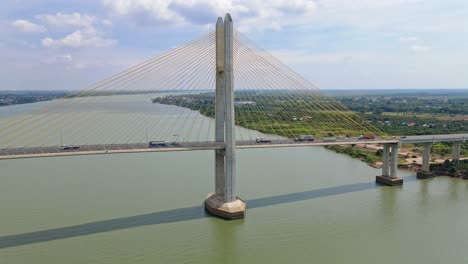 Aerial-flight-towards-famous-Tsubasa-bridge-with-driving-cars-and-trucks-over-Mekong-River-and-rural-landscape-in-background