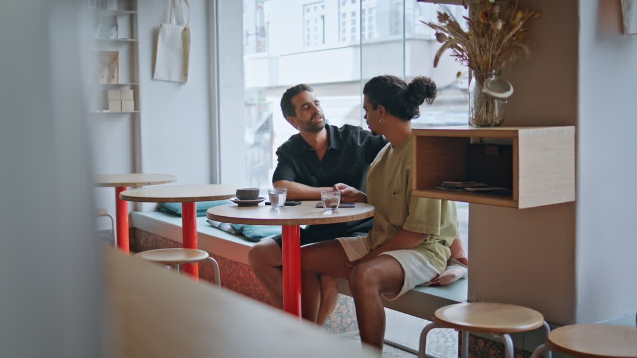 귀여운 동성애 커플이 앉아서 대화하는 테이블 카페. 부드러운 두 남자의 대화 데이트