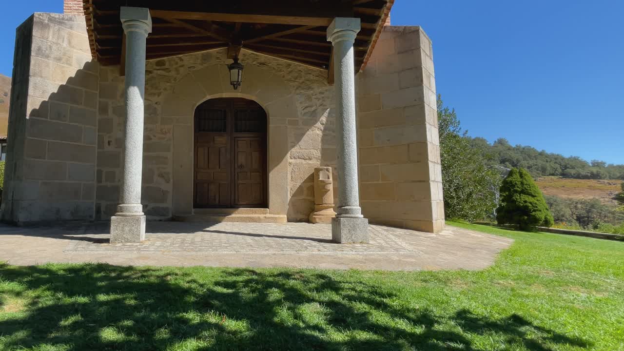 static shot of one of the entrances to the sanctuary of the Virgin of Chilla, with its two granite columns that support the wooden portico, the door and on one side an old font for crossing oneself