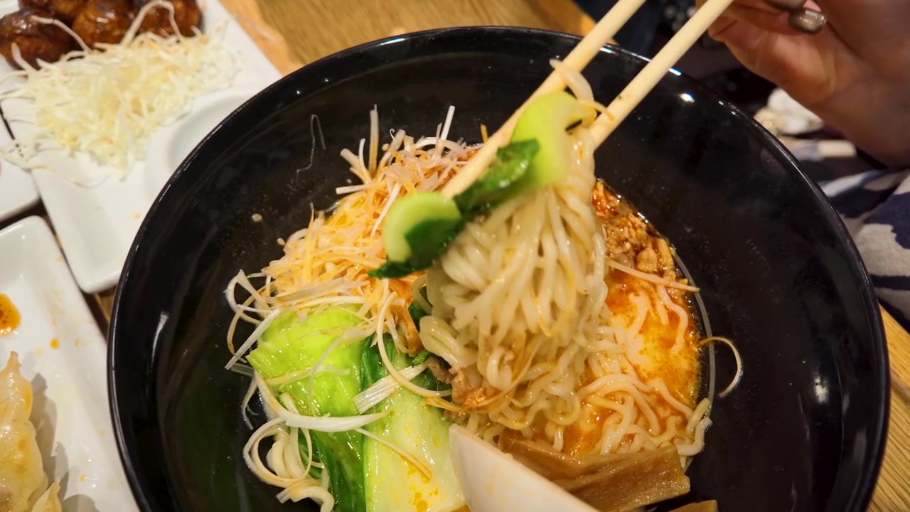 Personne mangeant des nouilles ramen épicées avec des baguettes dans un restaurant