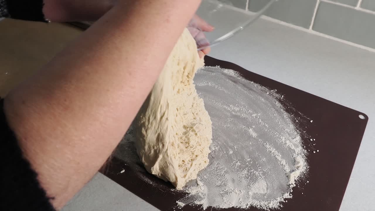 Mettere pane fatto in casa con lievito madre su una teglia infarinata in cucina.