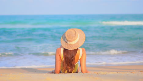 Back-of-Asian-woman-lying-on-the-beautiful-clean-sand-beach-watching-foamy-sea-tides-rolling-towards-her,-slow-motion