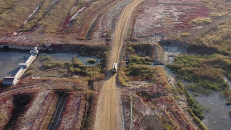 a-white-vehicle-running-between-native-plants-in-reclaimed-land