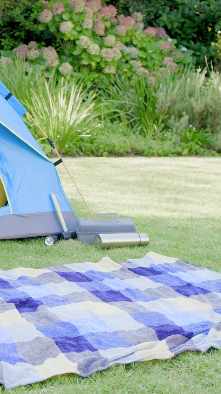 Vertical video: Panning camera in yard revealing tent opening and cushion for detail, copy space