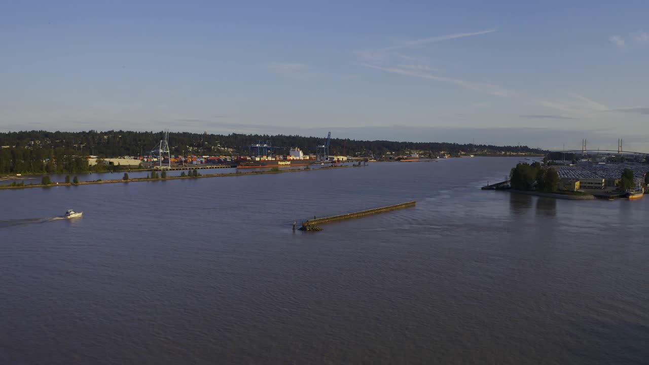 Aerial panaramic over industrial river as tugboat heads to the ocean to haul a shipping freightor into the industry shore for import export purposes of improving logistical processing of parcels