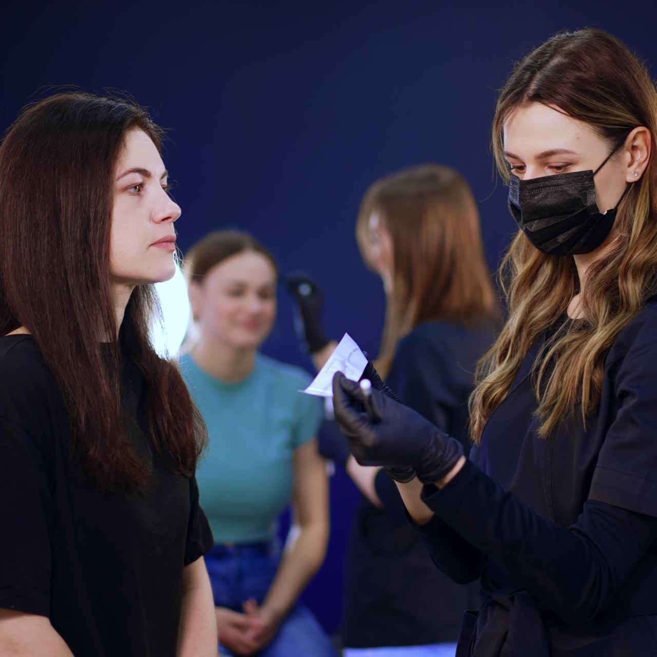 Beauty salon with clients and professionals. Eyebrow master stands in front of a client preparing materials