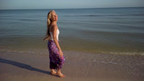 Mujer-Bastante-Madura-Sonriendo-Y-Caminando-Por-Una-Playa-Vestida-Con-Un-Sarong-Y-Luciendo-Muy-Feliz