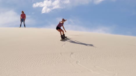 Woman-sand-boarding-while-man-watching-her-4k