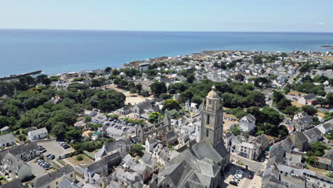 circular tracking aerial reveals town with church tower next to salt marshes of guérande