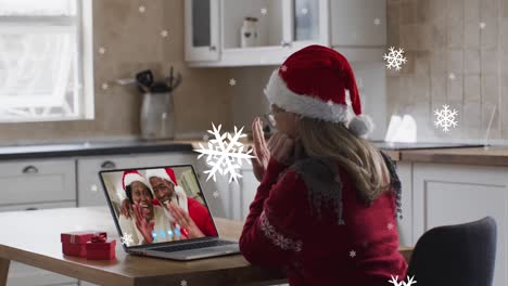 Animation-of-snow-falling-over-happy-caucasian-woman-in-santa-hat-on-laptop-video-call