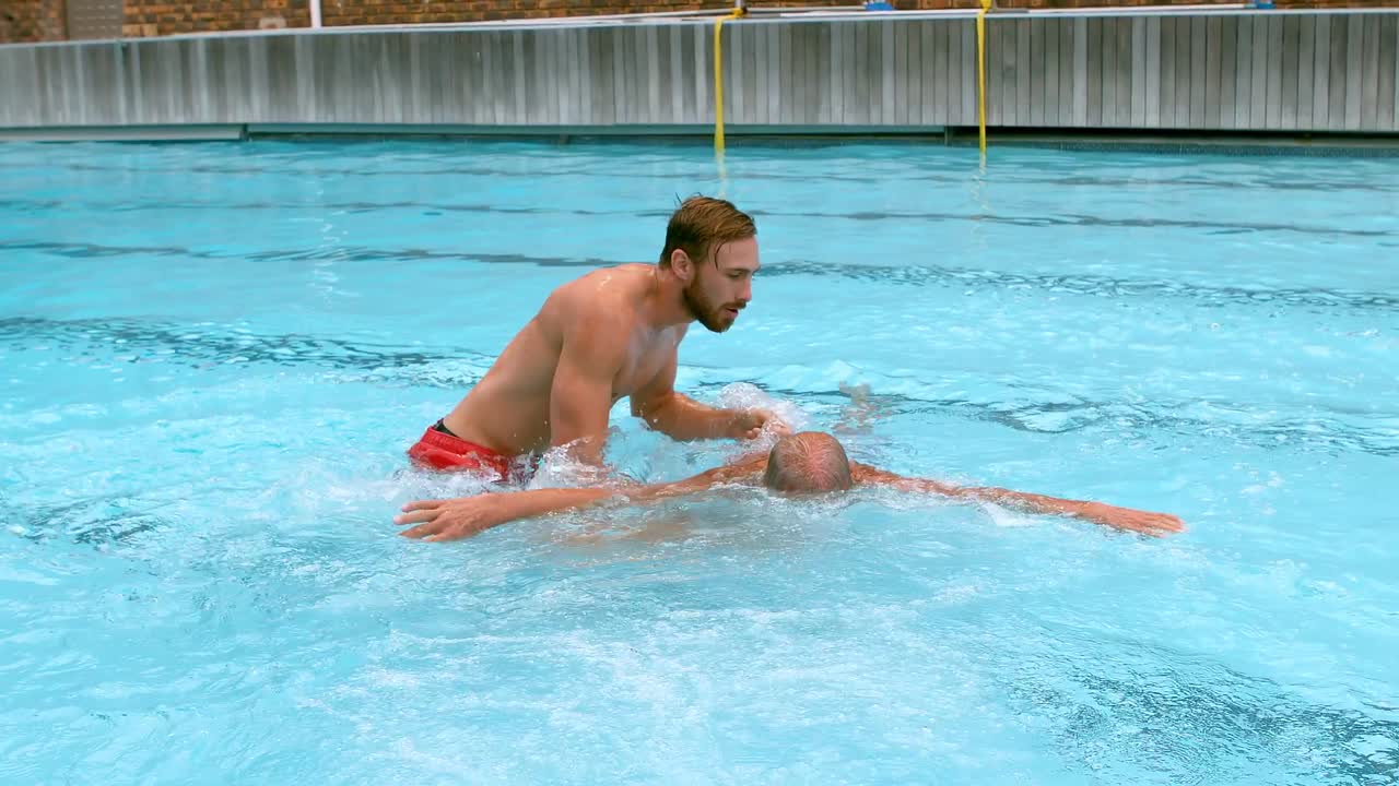 salvavidas rescatando a un hombre mayor de la piscina