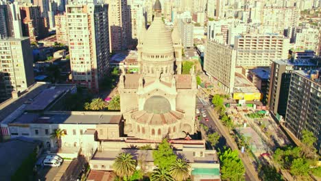 Aerial-view-establishing-tilt-up-of-Los-Sacramentinos-Church-in-a-residential-neighborhood-with-the-mountain-range-in-the-background,-Santiago,-Chile