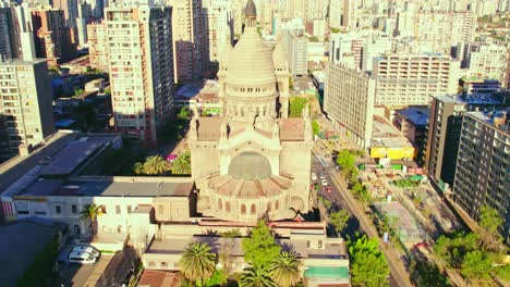 aerial view establishing tilt up of los sacramentinos church in a residential neighborhood with the mountain range in the background, santiago, chile