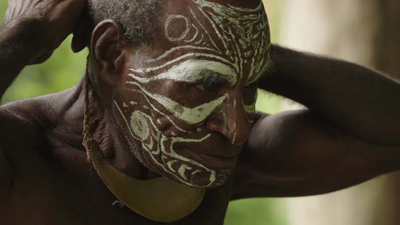 Close up shot, an Indigenous man adjusting his neck ornament.