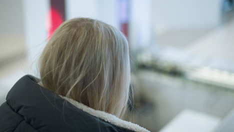close-up of career woman looking to her right while on a moving escalator in a mall, light blinking in the blurred background adds a modern touch to this urban scene