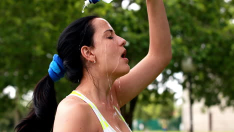 Bonita-Morena-Bebiendo-De-Una-Botella-De-Agua-Vertiéndose-Agua-Sobre-Ella-Misma.