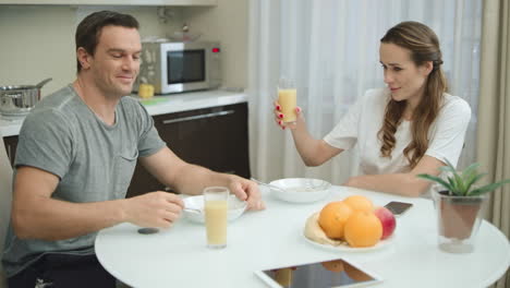 cheerful couple making cheers with orange juice.