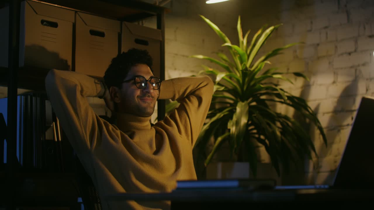 Man relaxing at his desk at night