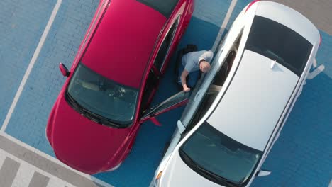joven conductor discapacitado entrando en un coche rojo de silla de ruedas