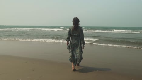 Women-walking-in-slow-motion-towards-water-in-long-flowing-green-dress