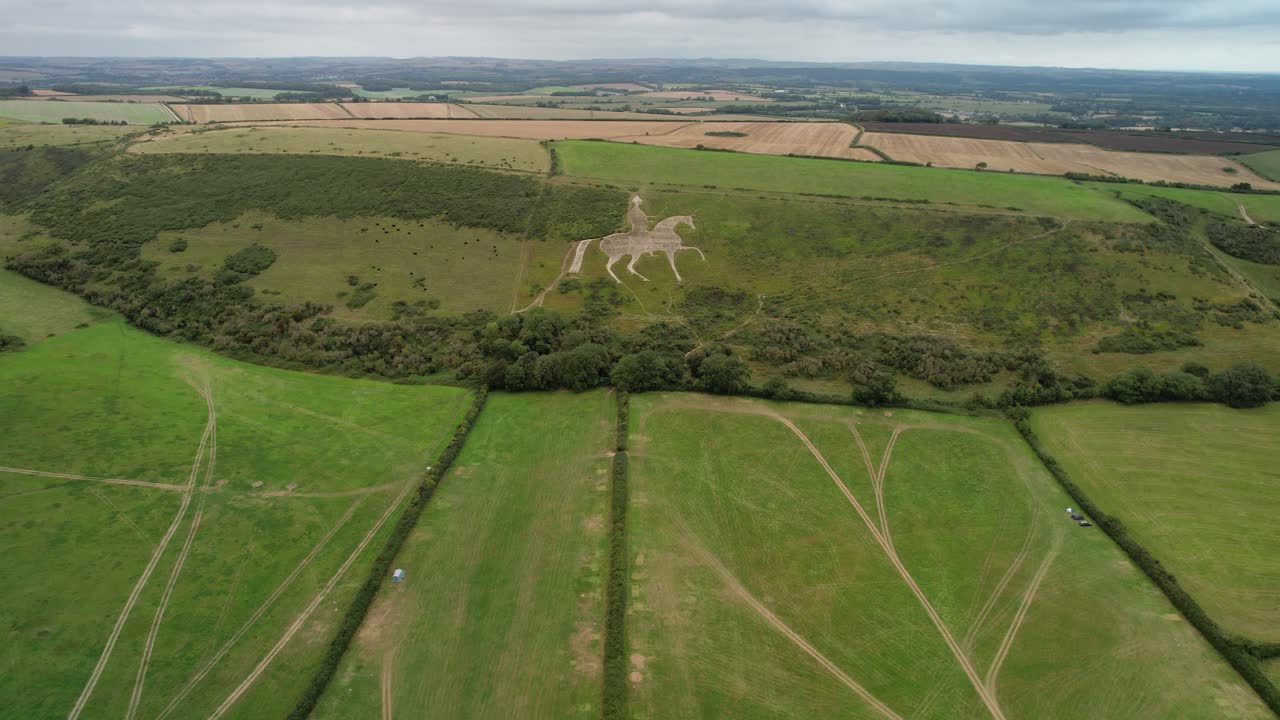 Osmington White Horse legendary chalk figure art on hillside slope aerial view wide pull away