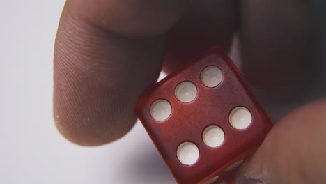 man holds dice with six spots on side on white background